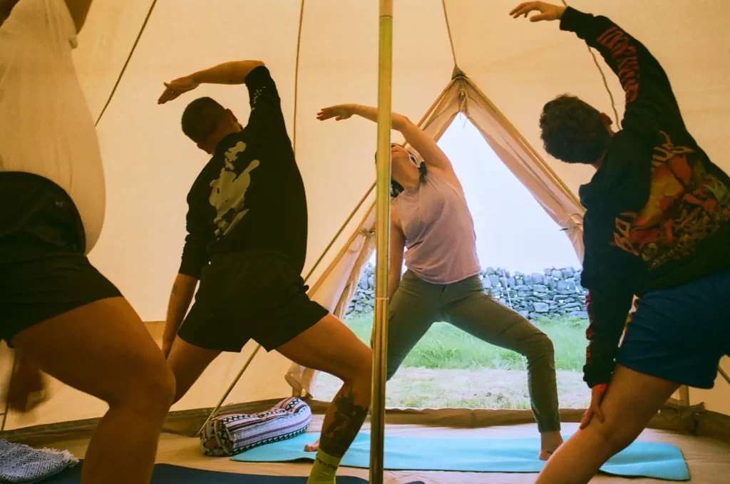 Participants engaging in a yoga session inside a tent at Éalú Aran's wellness retreat on Inis Oírr, surrounded by nature and a serene landscape.