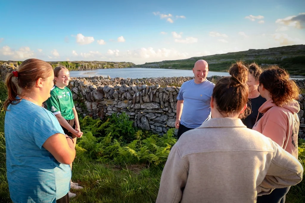 1G4A9179.00_00_50_14.Still004 Áine Seoighe Group of people engaged in a wellness retreat on Inis Oírr, surrounded by nature, promoting relaxation and connection through yoga and breathwork at Éalú Aran.