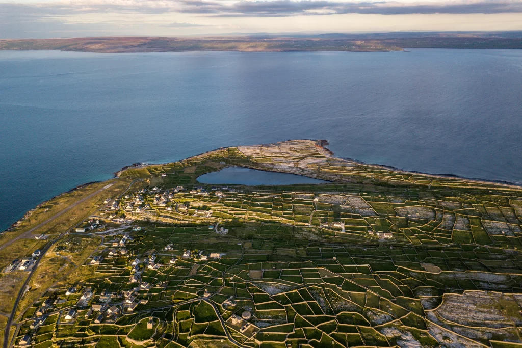 D3 - DJI_0016 Áine Seoighe Aerial view of Inis Oírr, showing green fields, stone walls, and the coastline meeting the sea.
