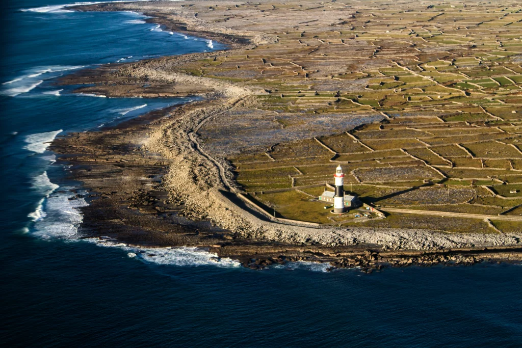 IMG_2661 Áine Seoighe Aerial view of Inis Oírr, featuring a lighthouse near the shoreline with rocky coastlines and green patches of land.