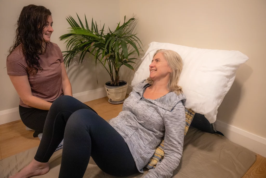 A wellness retreat session at Éalú Aran, featuring a relaxed interaction between two participants, promoting connection through yoga and breathwork amidst serene surroundings on Inis Oírr.